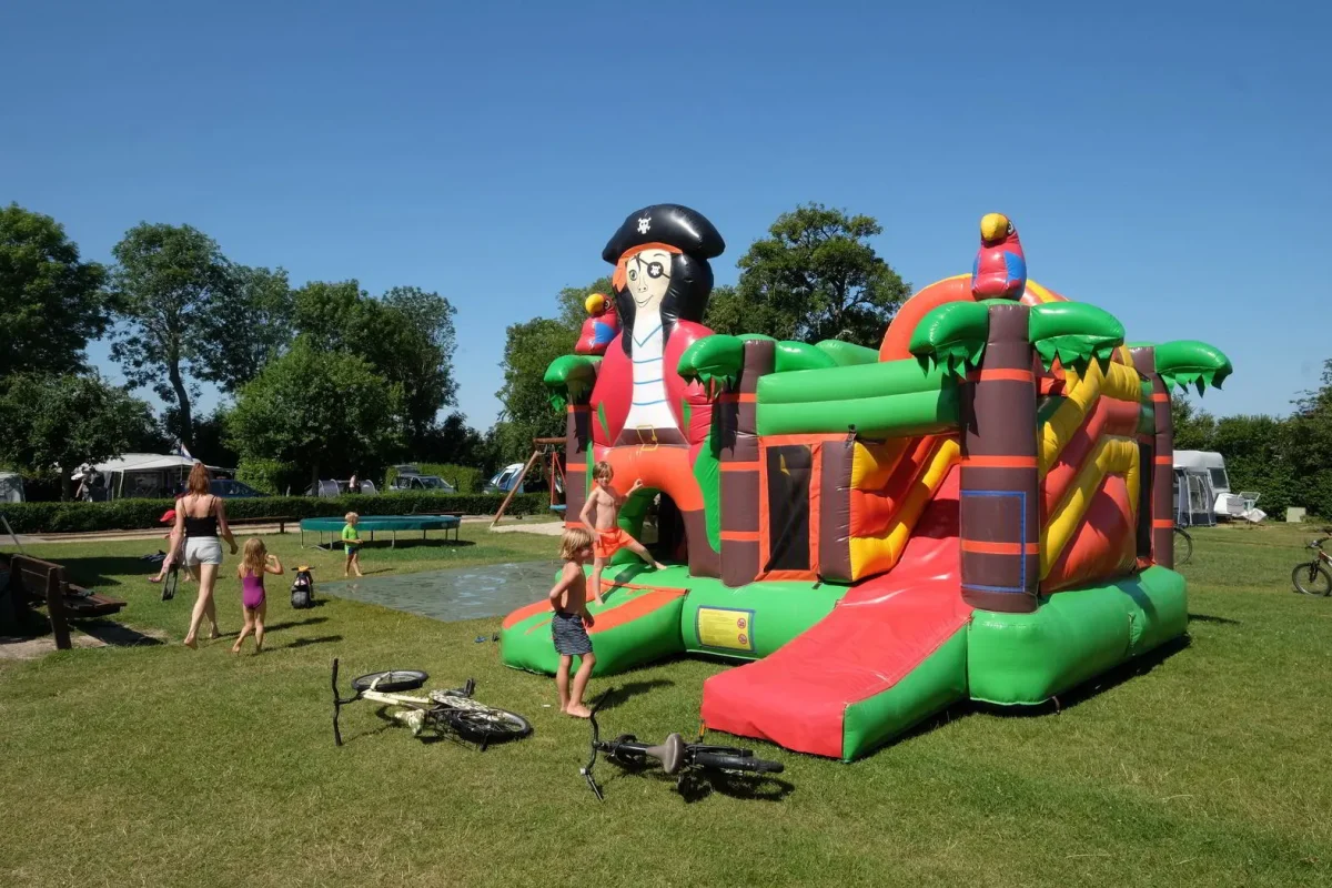 Kinderen op en rond een springkasteel op Camping Wulpen